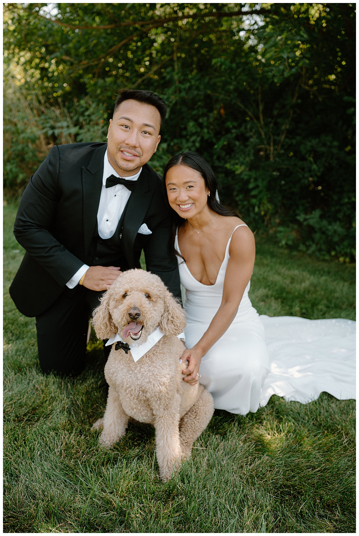 couple smiles while petting dog in a tie by Indigo Lace Collective