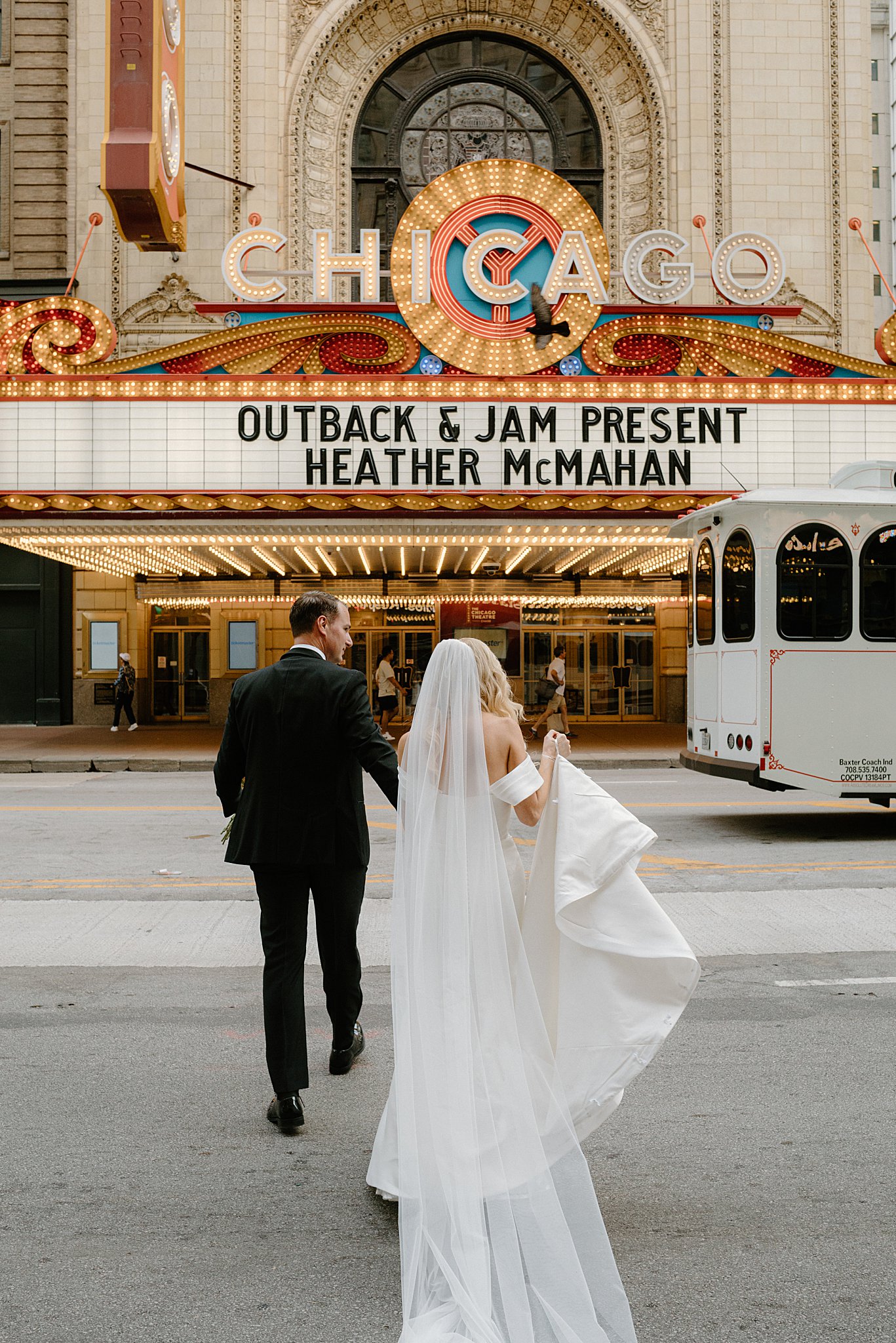 bride and groom cross street toward Chicago Theater by Midwest wedding photographer