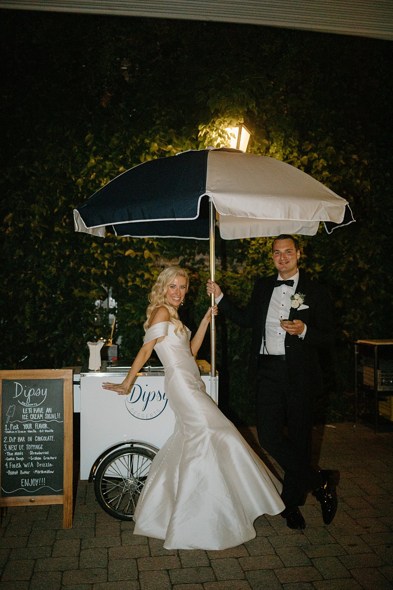 man and woman hold onto umbrella of ice cream cart during reception by Midwest wedding photographer