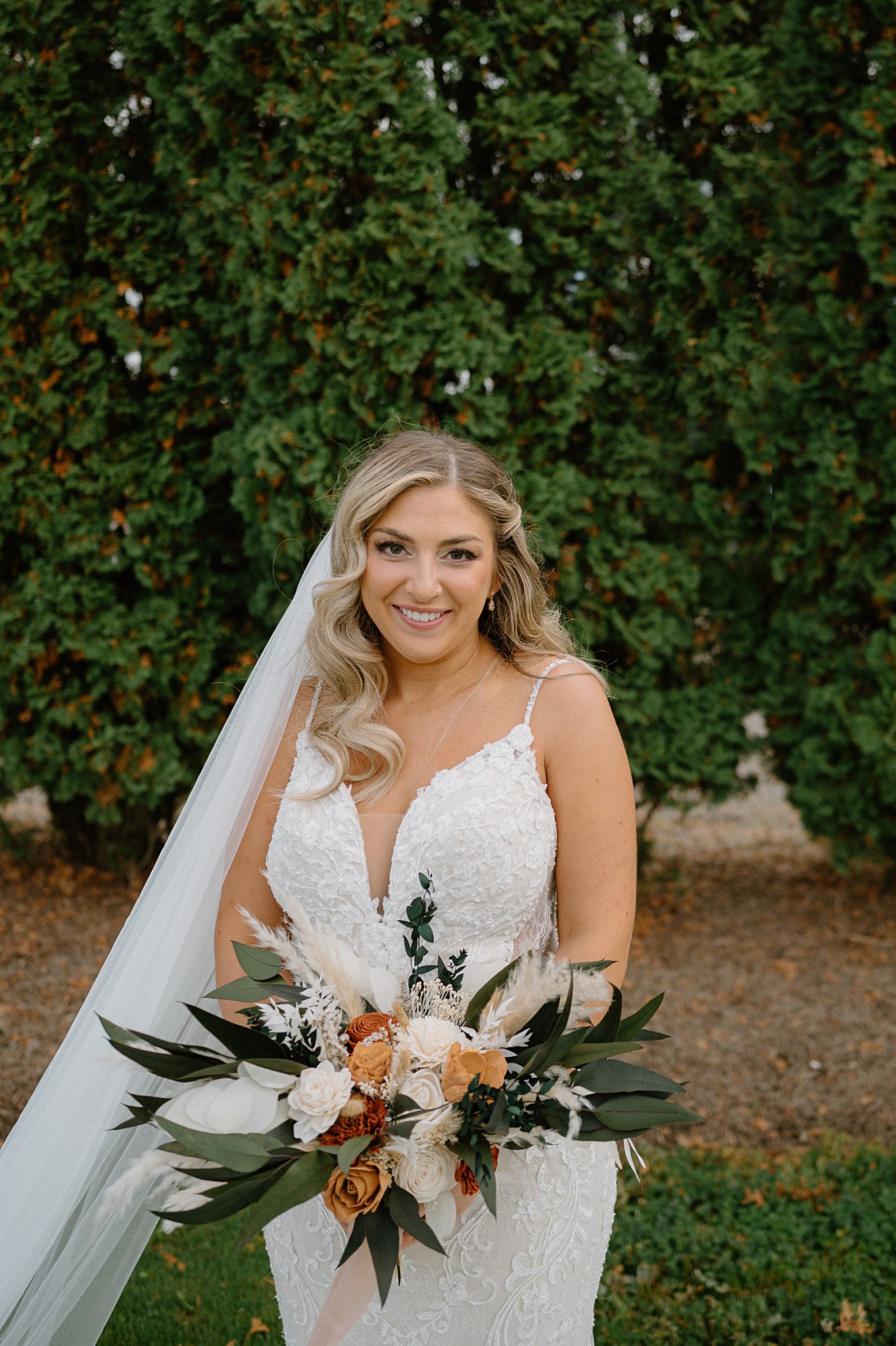 bride holds wedding florals as her veil blows in the wind by Midwest wedding photographer