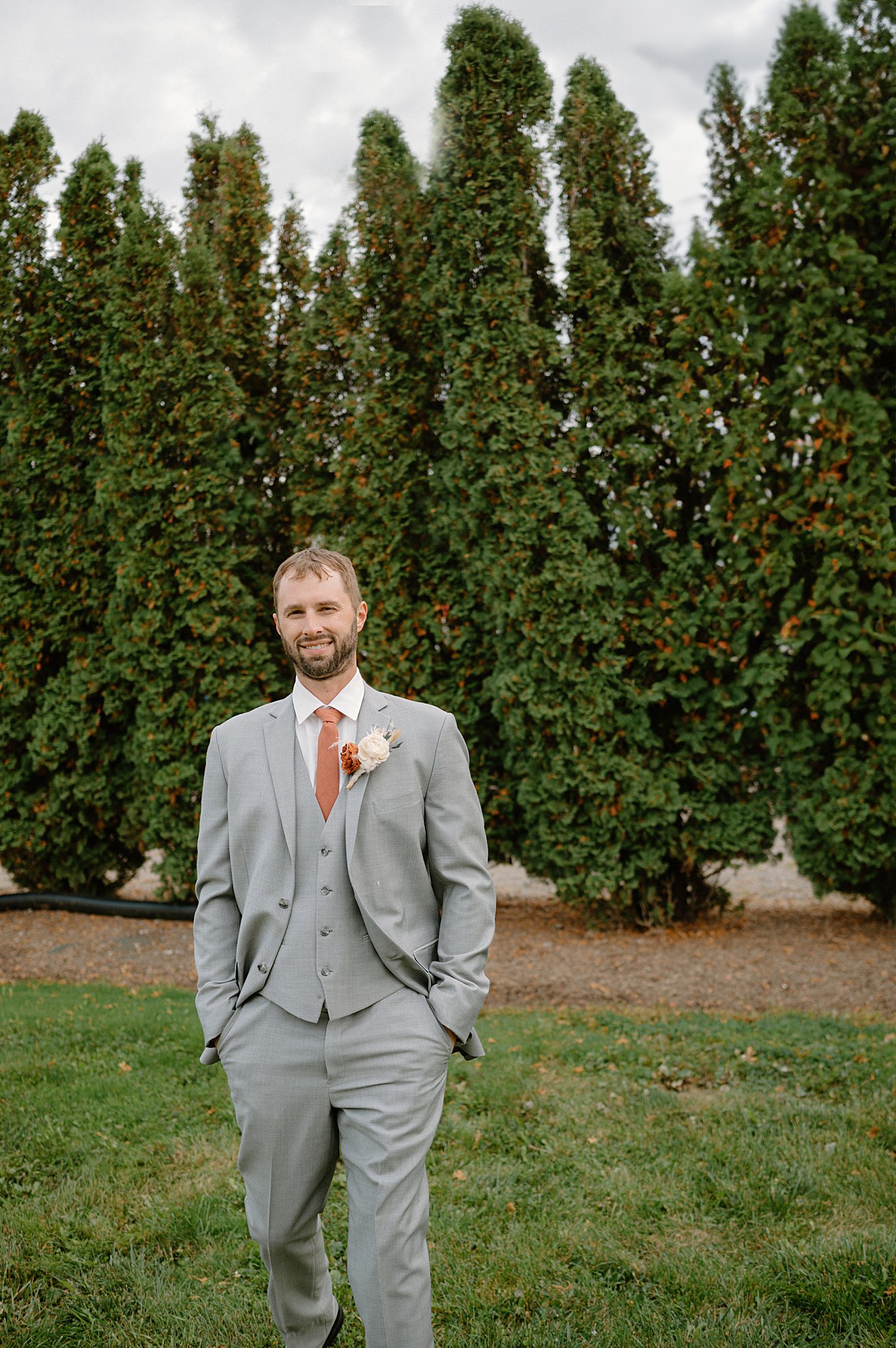 groom walks with hands in his pocket wearing a gray suit by Indigo Lace Collective